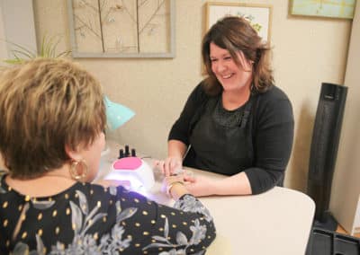 Woman smiling while she does another woman's nails